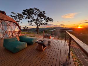 eine Terrasse mit Sofas und einem Tisch und ein Sonnenuntergang in der Unterkunft Domo Jacarandá in Tocos do Mogi