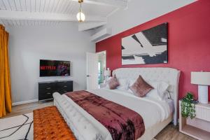 a bedroom with a large bed with a red wall at Lago Luxury Retreat - Sunset Views of Lake Travis in Lago Vista