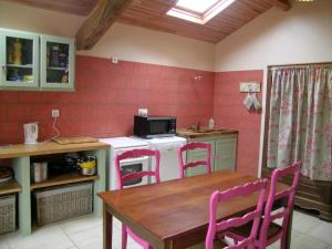 a kitchen with a table and pink chairs and a stove at Gîte familial avec pêche, cascade, animaux et activités variées, proche de Vichy et Le PAL - FR-1-489-122 in Barrais-Bussolles