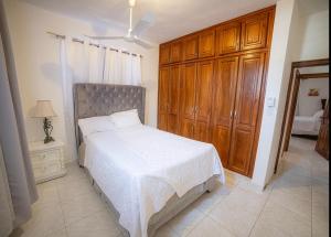 a bedroom with a white bed and a wooden cabinet at Spacious and secure villa in Puerto Plata