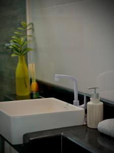 a white sink in a bathroom with a yellow vase at Flat Jijoca in Jijoca de Jericoacoara +4 photos