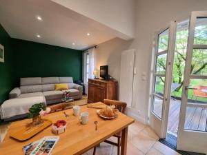 un soggiorno con un tavolo e un divano di Gîte charmant avec jardin, terrasse et tout confort à Saint-Galmier - FR-1-496-293 a Saint-Galmier