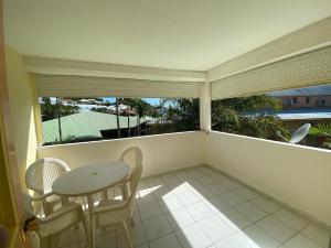 a balcony with a table and chairs and a window at APPARTEMENT AMARYLLIS 2 à 3 min de la PLAGE Pointe Marin in Sainte-Anne
