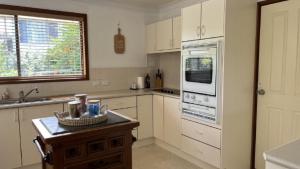 a kitchen with white appliances and a table with a basket at A Slice Of Paradise in Sussex Inlet