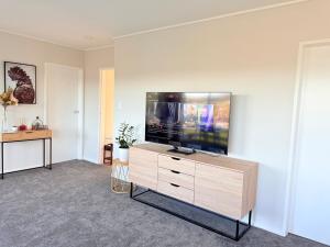 un salon avec une grande télévision à écran plat sur un mur dans l'établissement Renovated Entire 2BR Flat, Comfort, Scenic Views, Free Parking & 10 min to Ferry, à Wellington 47 autres photos
