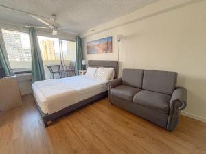 a bedroom with a bed and a couch at Mellow Kuhio Village Studio condo in Honolulu