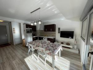ein Wohnzimmer mit Tisch und Küche in der Unterkunft Bel appartement T3 avec balcon sud et wifi, proche pistes - FR-1-787-130 in Laveissière