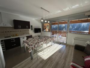 eine Küche mit Tisch und ein Esszimmer in der Unterkunft Bel appartement T3 avec balcon sud et wifi, proche pistes - FR-1-787-130 in Laveissière