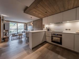 a kitchen with white cabinets and a living room at Appartement moderne Courchevel 1550, 4 personnes, parking, wifi - FR-1-631-234 in Courchevel