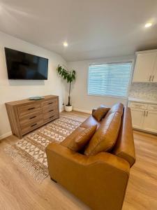 a living room with a brown leather couch and a flat screen tv at PRIVATE modern studio Guesthouse in Los Angeles
