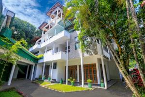 une vue extérieure d'une maison avec des arbres dans l'établissement King's Court Kandy, à Kandy