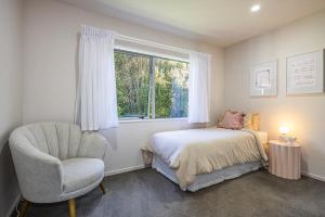 een slaapkamer met een bed, een stoel en een raam bij Modern on Miro in Ohakune