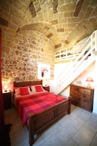 1 dormitorio con 1 cama en una pared de piedra en La Corte Delle Sterne, en Morciano di Leuca