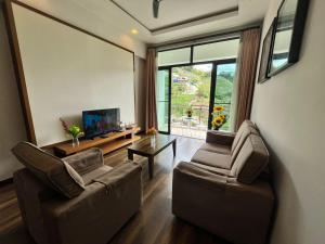 a living room with two chairs and a flat screen tv at The Retreat Mountain n Sunrise view Hilltop Hotel Apartment in Cameron Highlands in Brinchang