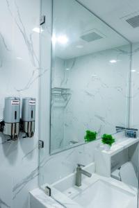 a white bathroom with a sink and a mirror at YMCA Makati in Manila