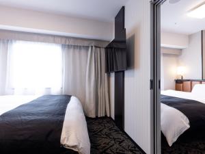 a hotel room with two beds and a sliding glass door at APA Hotel Nagoya Sakae Ekimae EXCELLENT in Nagoya