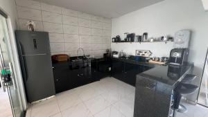 cocina con armarios negros y nevera en Darocha Salinas, en Salinópolis