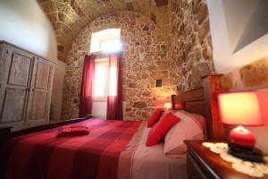 Un dormitorio con una cama con almohadas rojas y una ventana en La Corte Delle Sterne, en Morciano di Leuca