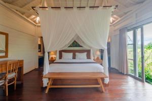 a bedroom with a large bed with a canopy at Precious Journey Retreat in Ubud