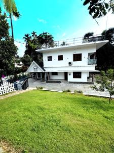 a white house with a lawn in front of it at Luxury Villa Ps5 Home-Theater Hookah 20km 2 Munnar in Chillithodu