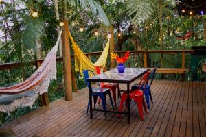 a table and chairs on a deck with hammocks at Chalés Canto do Dragão in Guabiruba