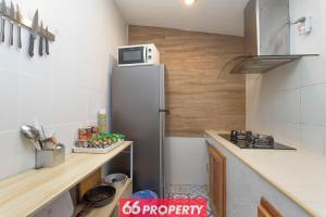 a kitchen with a refrigerator with a microwave on top at Nimman Home with Cozy Patio - Workspace w Screen in Chiang Mai