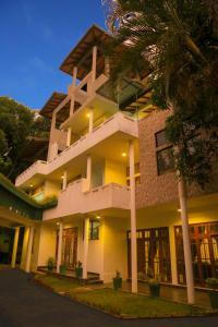 un grand bâtiment avec des palmiers devant dans l'établissement King's Court Kandy, à Kandy