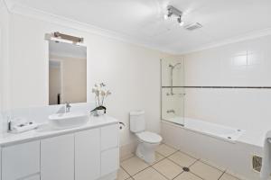a white bathroom with a sink and a toilet at Cairns City Apartments in Cairns