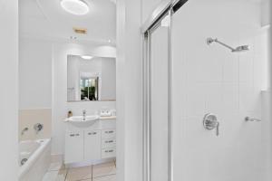 a white bathroom with a shower and a sink at Cairns City Apartments in Cairns
