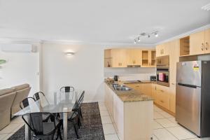 a kitchen with a table and a stainless steel refrigerator at Cairns City Apartments in Cairns