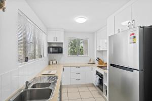a kitchen with white cabinets and a stainless steel refrigerator at Cairns City Apartments in Cairns