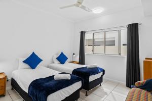 two beds in a room with a window at Cairns City Apartments in Cairns