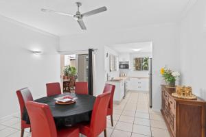 a kitchen and dining room with a black table and red chairs at Cairns City Apartments in Cairns