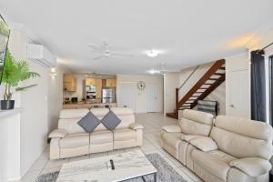 a living room with two couches and a staircase at Cairns City Apartments in Cairns