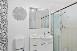 a white bathroom with a toilet and a sink at Cairns City Apartments in Cairns