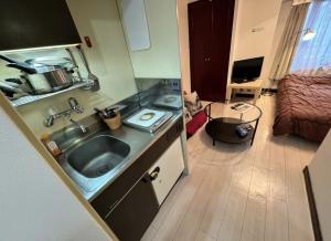 a small kitchen with a sink and a bedroom at 京橋プルトンビル in Osaka