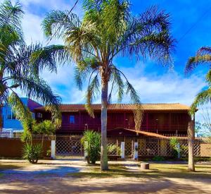 ein Haus mit Palmen davor in der Unterkunft Pousada Laranjal em Pelotas in Pelotas