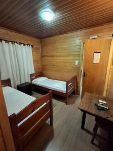 ein kleines Zimmer mit zwei Betten und einem Tisch in der Unterkunft Pousada Laranjal em Pelotas in Pelotas