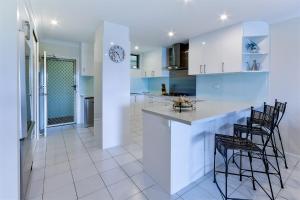 a kitchen with white cabinets and a counter with chairs at Poinciana Lodges in Hamilton Island +14 photos