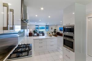 a kitchen with white cabinets and a stove top oven at Poinciana Lodges in Hamilton Island
