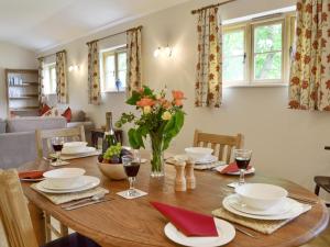 une salle à manger avec une table en bois et des verres de vin dans l'établissement Woodlands Dairy Cottage, à Billingshurst