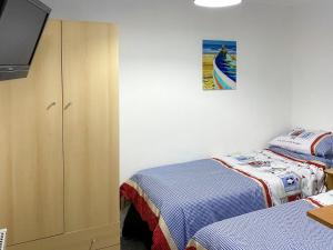 a bedroom with two beds and a tv and a cabinet at Sandy Cott in Kilkhampton +6 photos