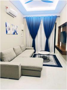 a living room with a couch and a blue curtain at Maldira Homestay in Batu Gajah in Gua Sai
