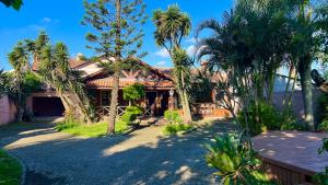 a house with palm trees in front of it at Ampla e luxuosa casa com áreas de lazer in Pelotas