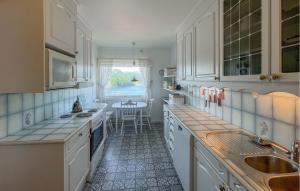 a kitchen with white cabinets and a sink and a table at 3 Bedroom Amazing Home In Farsund in Farsund