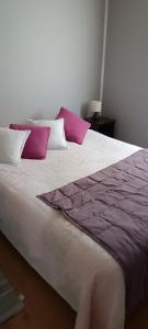 a large bed with purple and white pillows on it at Cabaña Puente Viejo, Los Lagos in Los Lagos