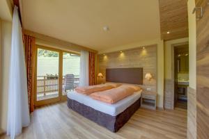a bedroom with a large bed and a balcony at Ferienwohnung & Spa Access Zimmerhofer in Cadipietra