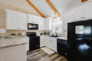 a kitchen with white cabinets and a black refrigerator at Relaxing Cabin Retreat with private beach swimming area in Hot Springs