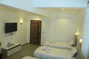 a hotel room with two beds and a flat screen tv at khufus pyramids hotel in Cairo