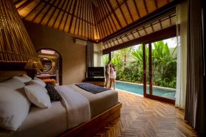 two people standing in a bedroom with a bed and a pool at Asvara Resort & Spa Ubud by Ini Vie Hospitality in Ubud +27 photos